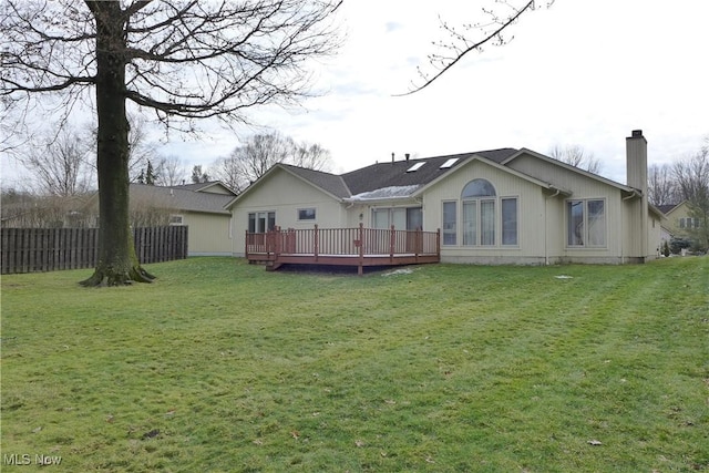 rear view of house featuring a deck and a lawn