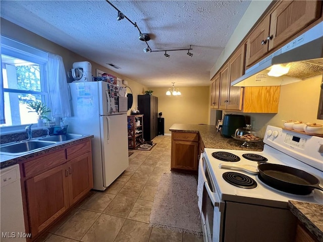 kitchen featuring sink, white appliances, a notable chandelier, a textured ceiling, and decorative light fixtures