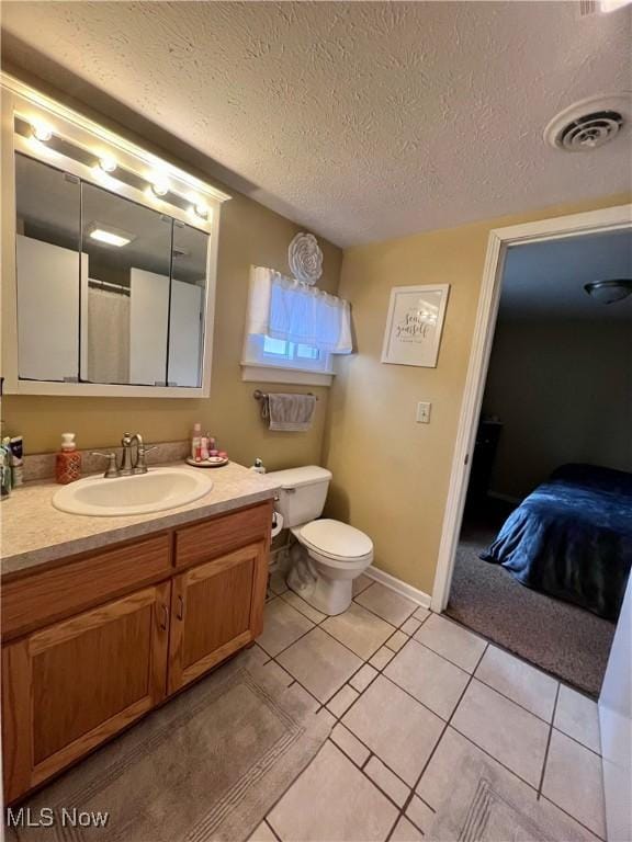 bathroom with vanity, tile patterned flooring, toilet, and a textured ceiling