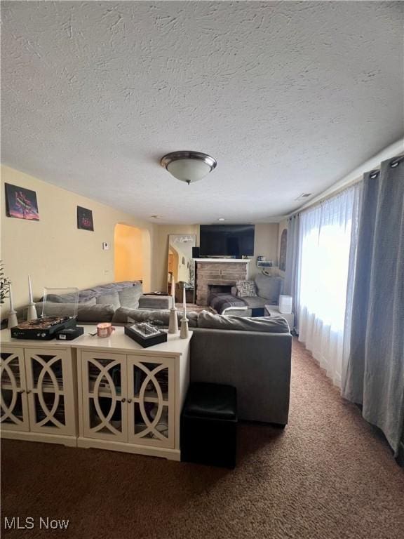 living room with a fireplace, a textured ceiling, and carpet flooring