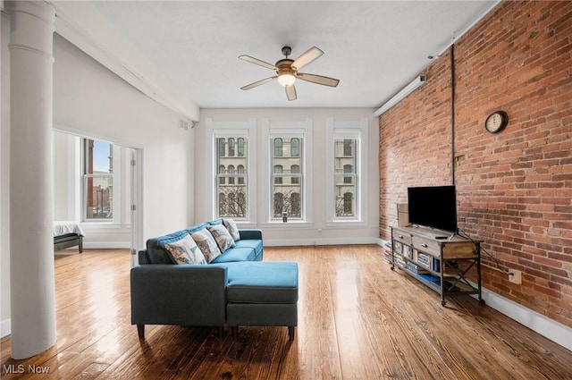 living room featuring ceiling fan, brick wall, hardwood / wood-style floors, and ornate columns