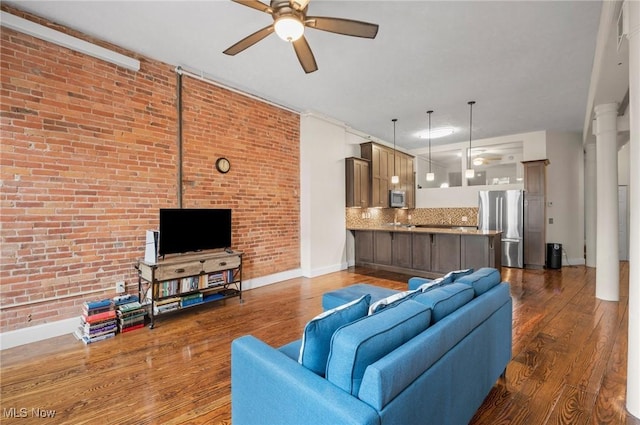 living room with ceiling fan, brick wall, dark hardwood / wood-style floors, and decorative columns