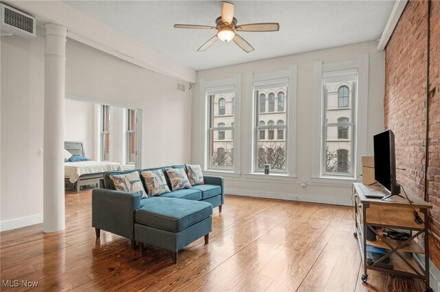 living room with brick wall, ceiling fan, and light wood-type flooring