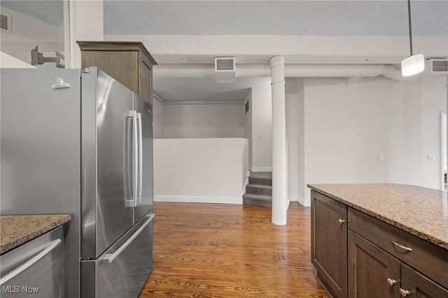 kitchen with light stone countertops, wood finished floors, visible vents, freestanding refrigerator, and dark brown cabinets