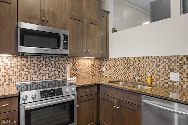 kitchen featuring stainless steel appliances, sink, and dark stone counters