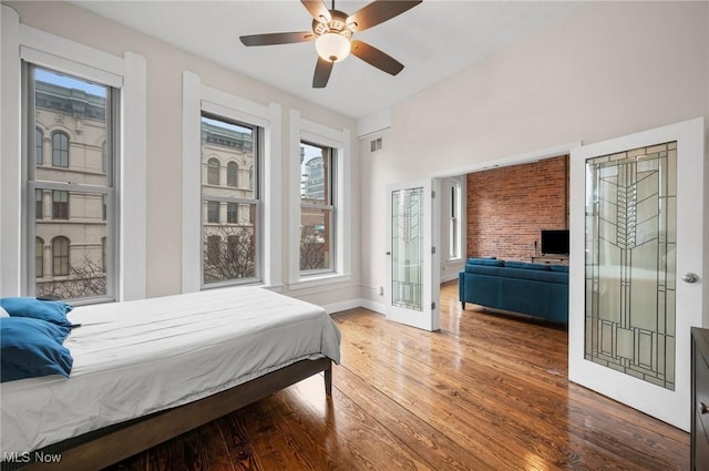 bedroom featuring a ceiling fan, visible vents, wood finished floors, and baseboards