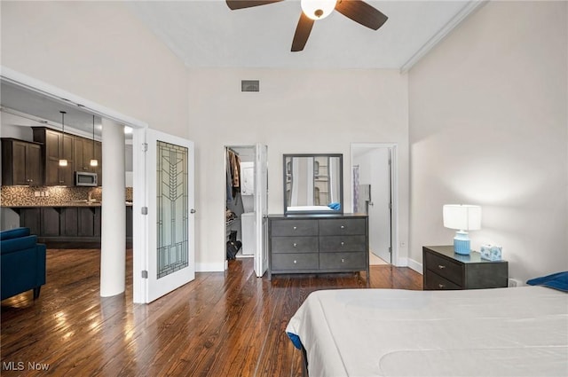 bedroom with visible vents, a walk in closet, baseboards, and dark wood-style flooring