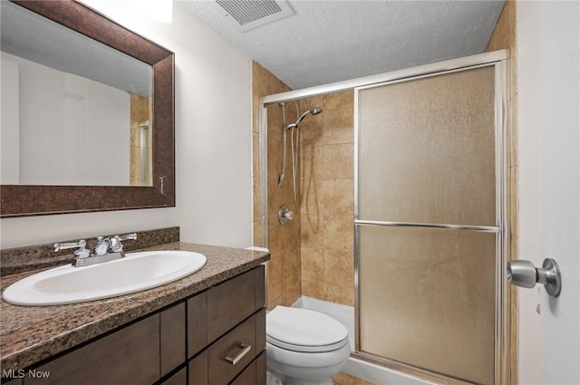 bathroom with vanity, toilet, an enclosed shower, and a textured ceiling