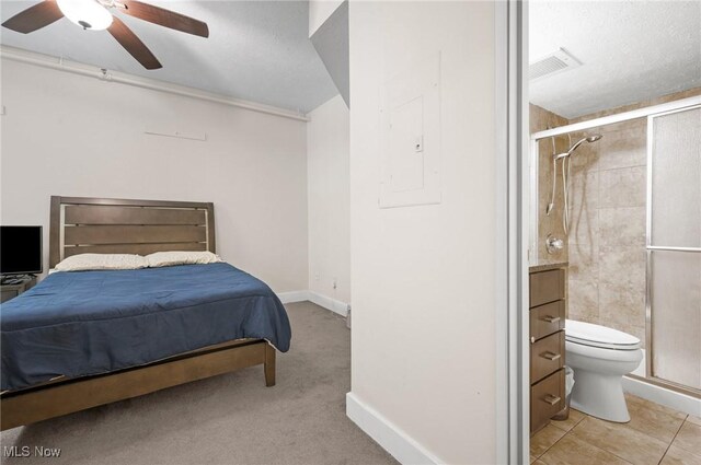 bedroom with light tile patterned floors, ensuite bath, electric panel, and ceiling fan