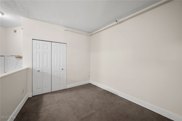 unfurnished bedroom with visible vents, a textured ceiling, a closet, carpet flooring, and baseboards