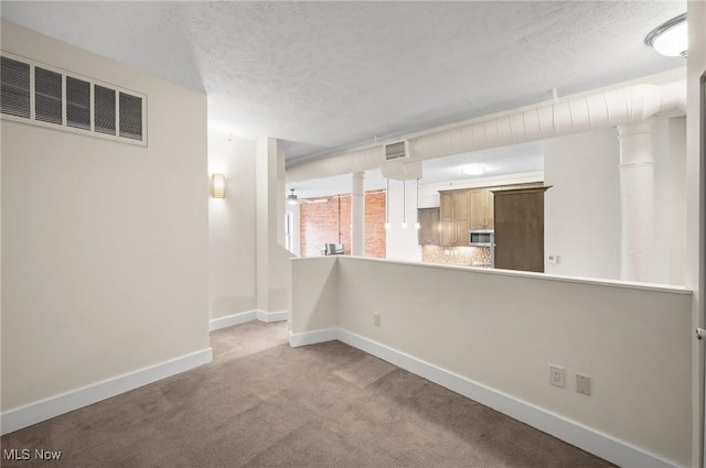 spare room with light colored carpet and a textured ceiling