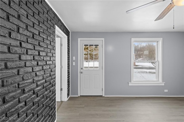 entryway featuring hardwood / wood-style flooring, brick wall, and ceiling fan