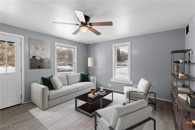 living room with a wealth of natural light, light hardwood / wood-style floors, and ceiling fan