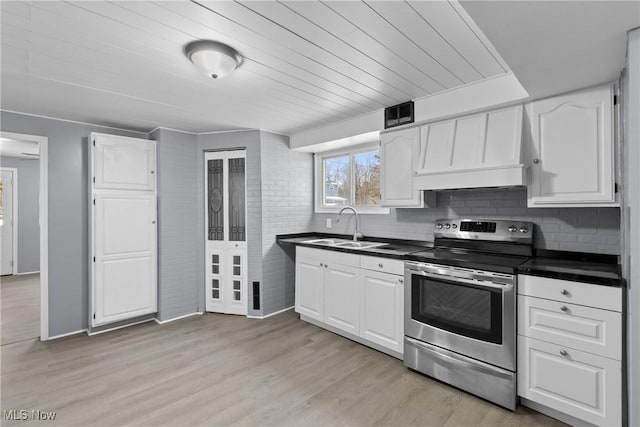 kitchen featuring premium range hood, sink, white cabinets, stainless steel range with electric stovetop, and light wood-type flooring