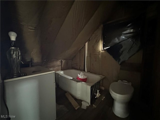 bathroom with lofted ceiling, vanity, toilet, and a washtub