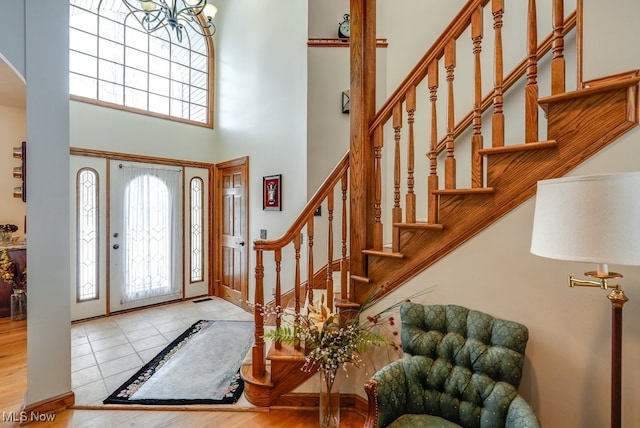 tiled foyer featuring a towering ceiling and a notable chandelier