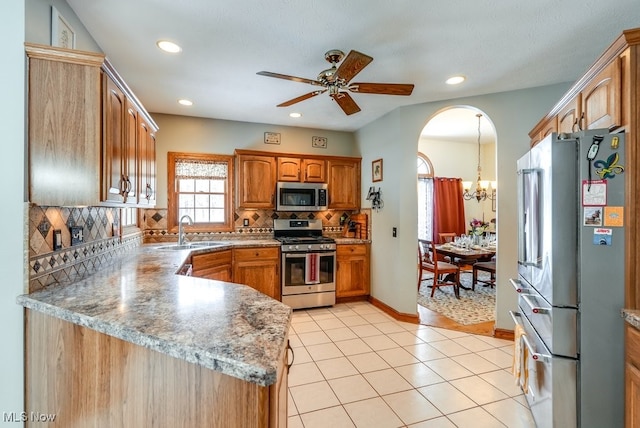 kitchen with sink, light tile patterned floors, stainless steel appliances, tasteful backsplash, and kitchen peninsula