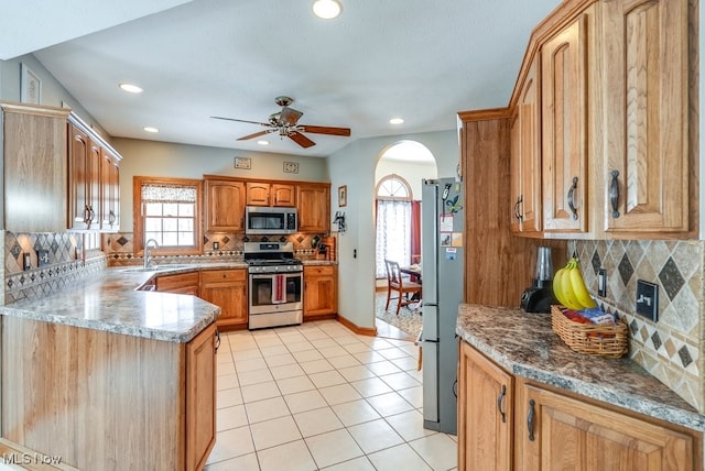 kitchen with sink, tasteful backsplash, light tile patterned floors, appliances with stainless steel finishes, and kitchen peninsula