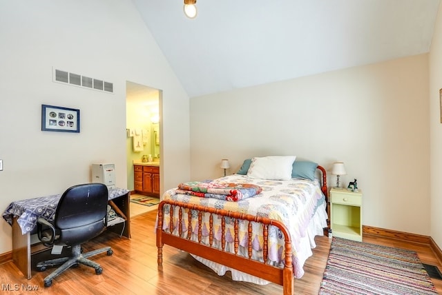 bedroom with wood-type flooring, ensuite bathroom, and high vaulted ceiling