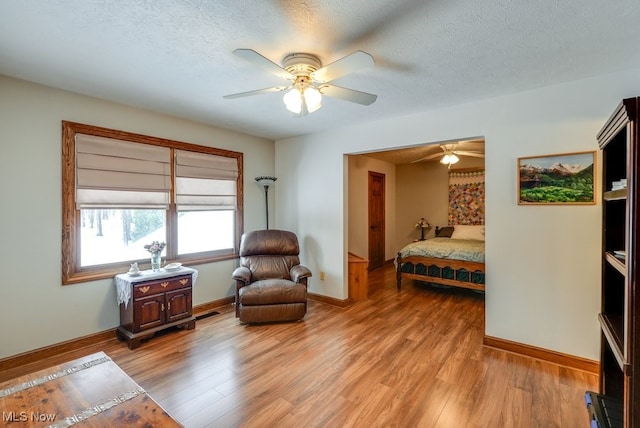 bedroom featuring ceiling fan, light hardwood / wood-style floors, and a textured ceiling