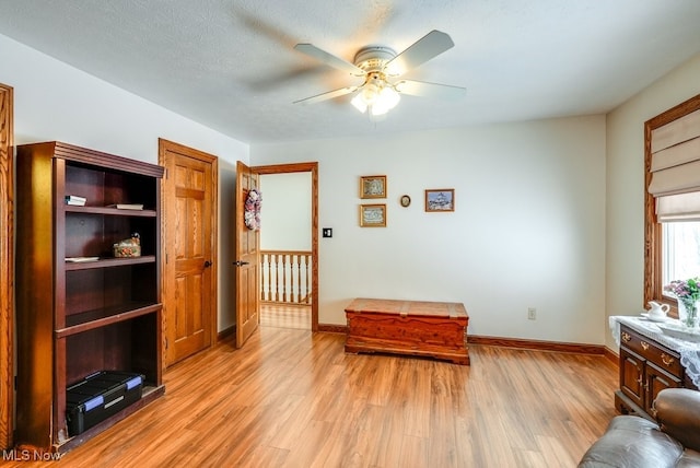 living area featuring ceiling fan, a textured ceiling, and light hardwood / wood-style flooring