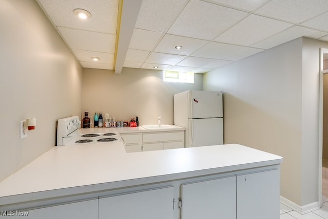 kitchen featuring sink, a paneled ceiling, white appliances, and kitchen peninsula