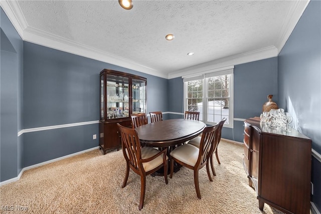 carpeted dining room with ornamental molding and a textured ceiling