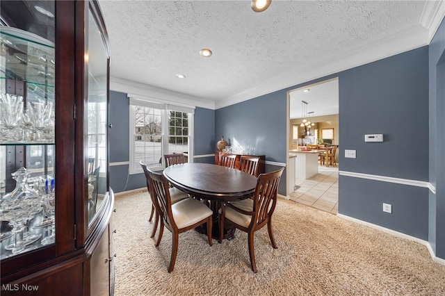 dining space with an inviting chandelier, ornamental molding, light carpet, and a textured ceiling