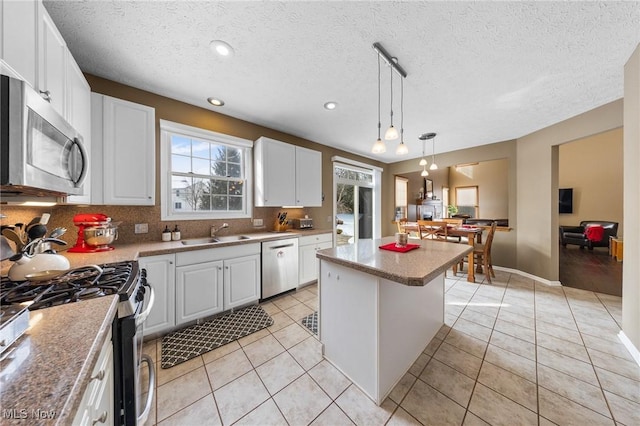 kitchen featuring pendant lighting, white cabinetry, sink, a center island, and stainless steel appliances