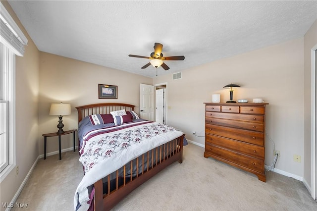 carpeted bedroom with ceiling fan and a textured ceiling