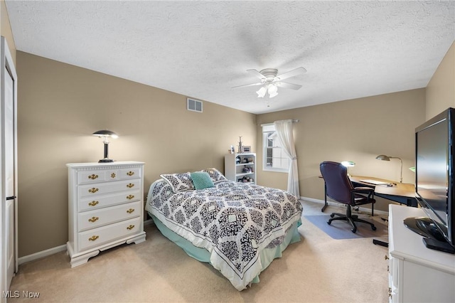 bedroom featuring ceiling fan, light carpet, and a textured ceiling