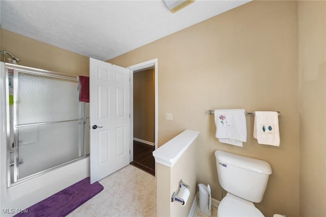 bathroom featuring a textured ceiling, toilet, and combined bath / shower with glass door