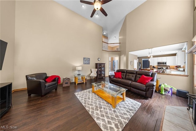 living room with ceiling fan, a towering ceiling, and dark hardwood / wood-style floors