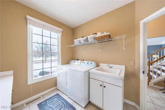 laundry room featuring sink, washer and clothes dryer, cabinets, and light tile patterned flooring