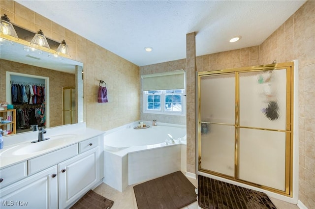 bathroom with tile walls, vanity, and separate shower and tub