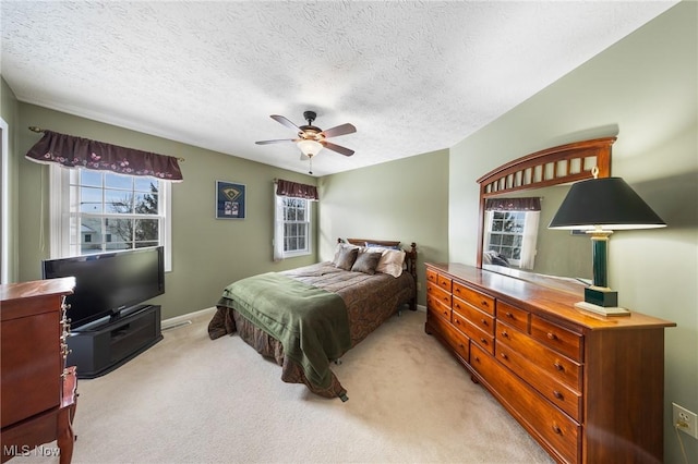 bedroom featuring ceiling fan, light colored carpet, and a textured ceiling