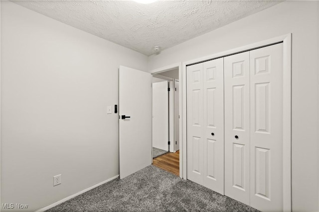 unfurnished bedroom with dark carpet, a closet, and a textured ceiling