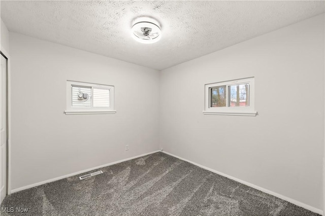 empty room featuring carpet and a textured ceiling