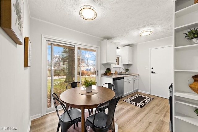 dining area with light hardwood / wood-style floors, sink, and a textured ceiling