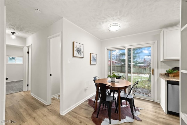 dining space with a textured ceiling and light hardwood / wood-style flooring