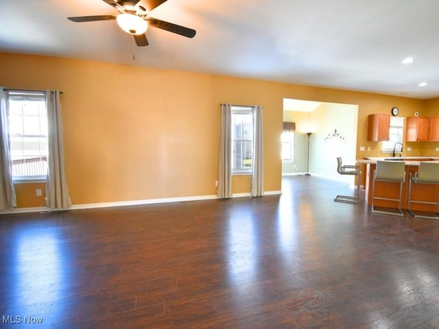 unfurnished living room with ceiling fan, plenty of natural light, dark hardwood / wood-style floors, and sink