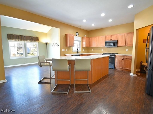 kitchen featuring dark wood-type flooring, stainless steel appliances, a breakfast bar, and a kitchen island