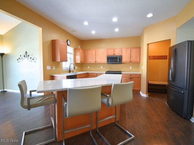 kitchen with light brown cabinetry, a breakfast bar, sink, fridge, and dark hardwood / wood-style flooring