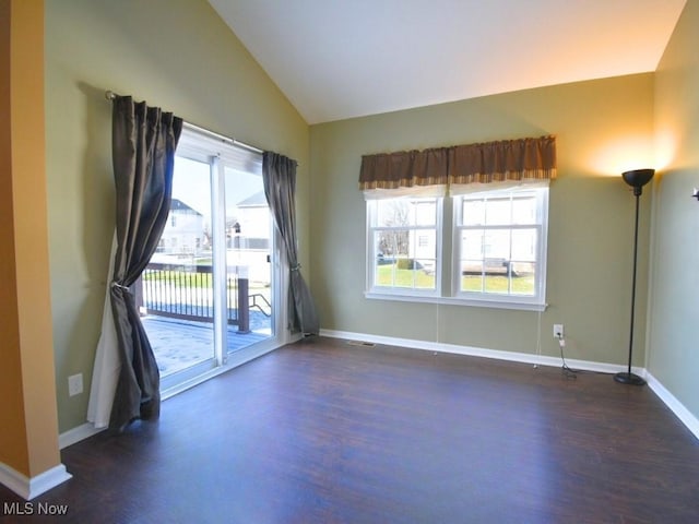 spare room with lofted ceiling, a healthy amount of sunlight, and dark hardwood / wood-style flooring