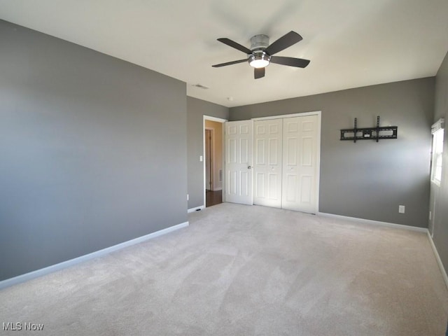 unfurnished bedroom with ceiling fan, light carpet, and a closet