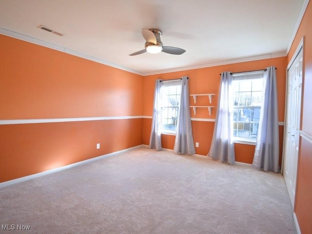 carpeted spare room with ceiling fan and ornamental molding