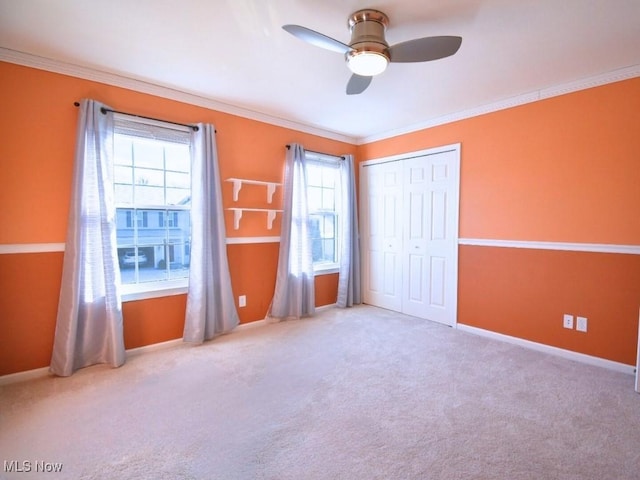 unfurnished bedroom with crown molding, light carpet, ceiling fan, and a closet