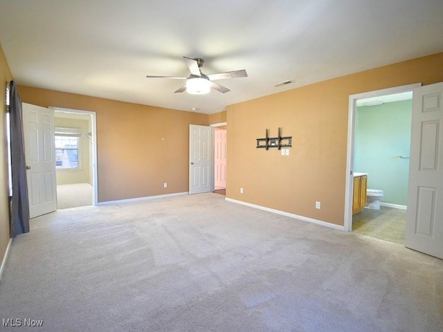 unfurnished bedroom featuring light carpet, ceiling fan, and ensuite bathroom