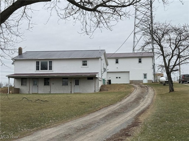 back of house with a garage and a lawn