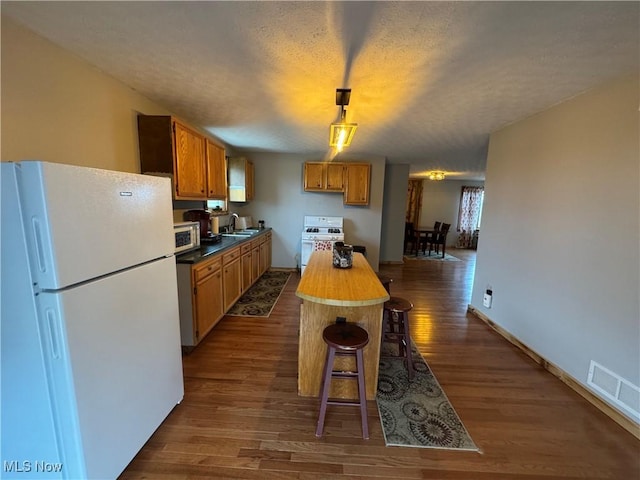 kitchen featuring sink, white appliances, wooden counters, hanging light fixtures, and dark hardwood / wood-style flooring